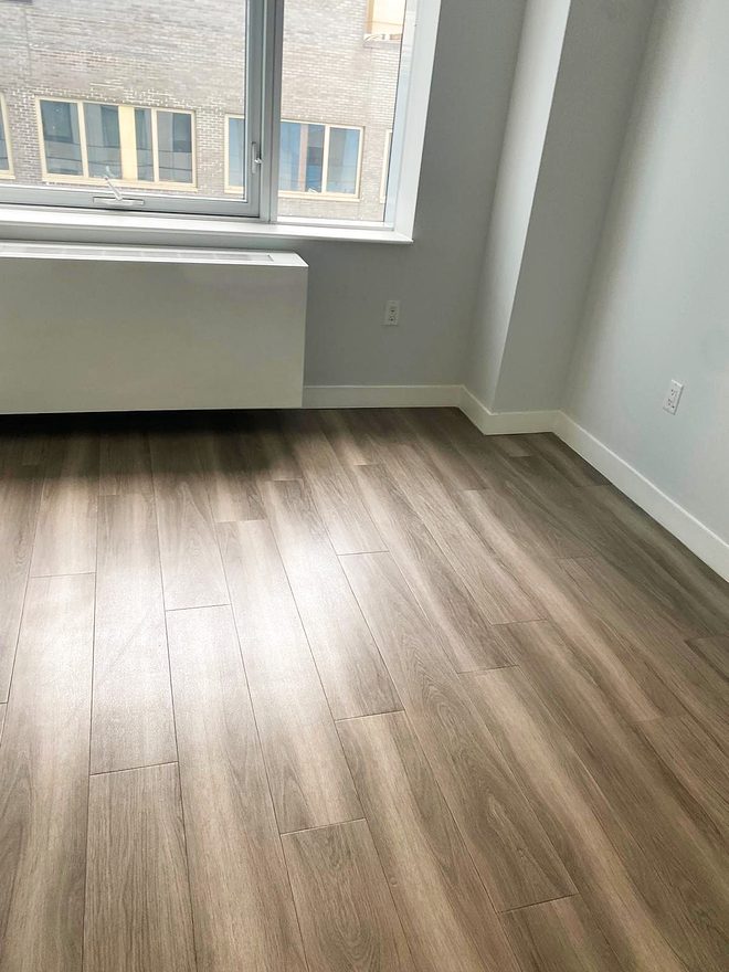 An empty living area with a clean plank floor and a bright window