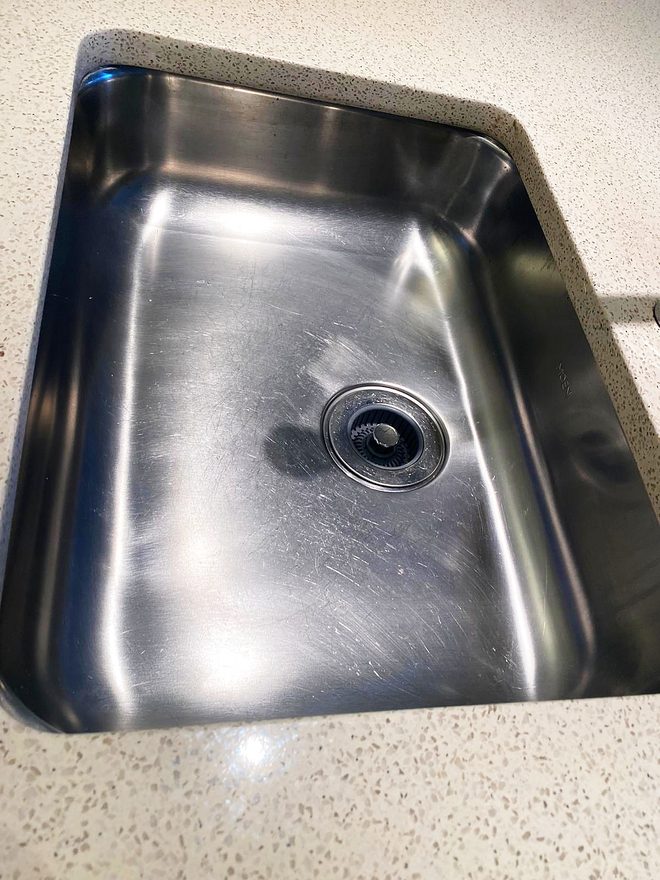 A deep stainless sink and drain, cleaned and dried